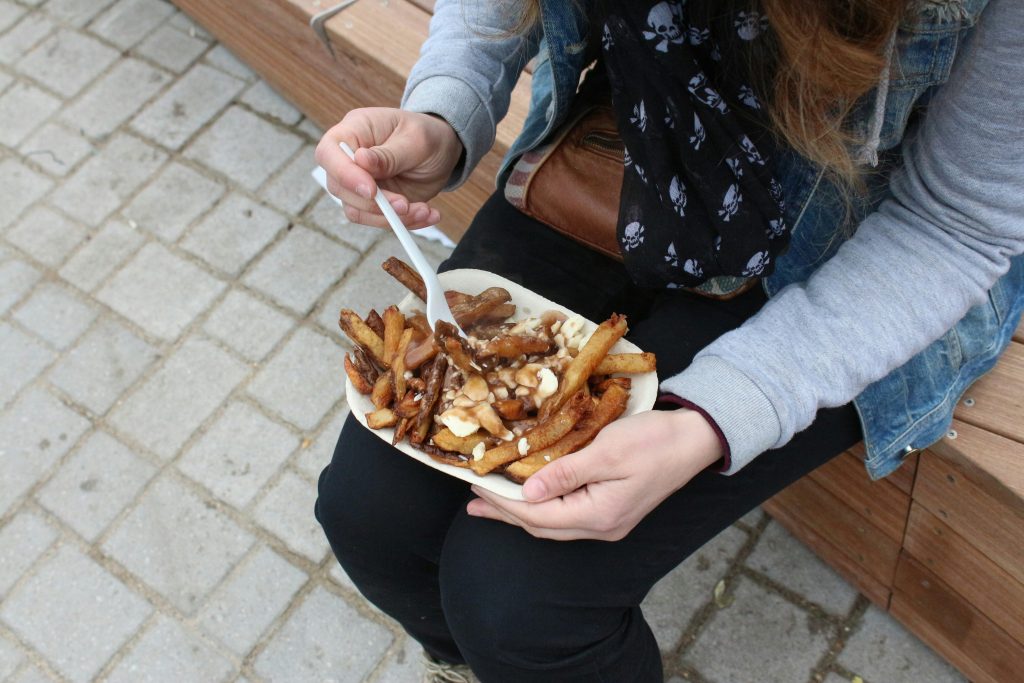 Montreal Attractions | Woman eating poutine | Evolve Tours