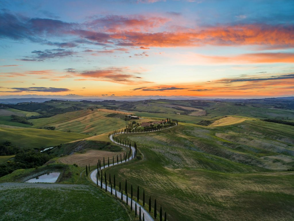 Books to Read Before Visiting Italy | Sunset over grassy hills in Tuscany | Evolve Tours