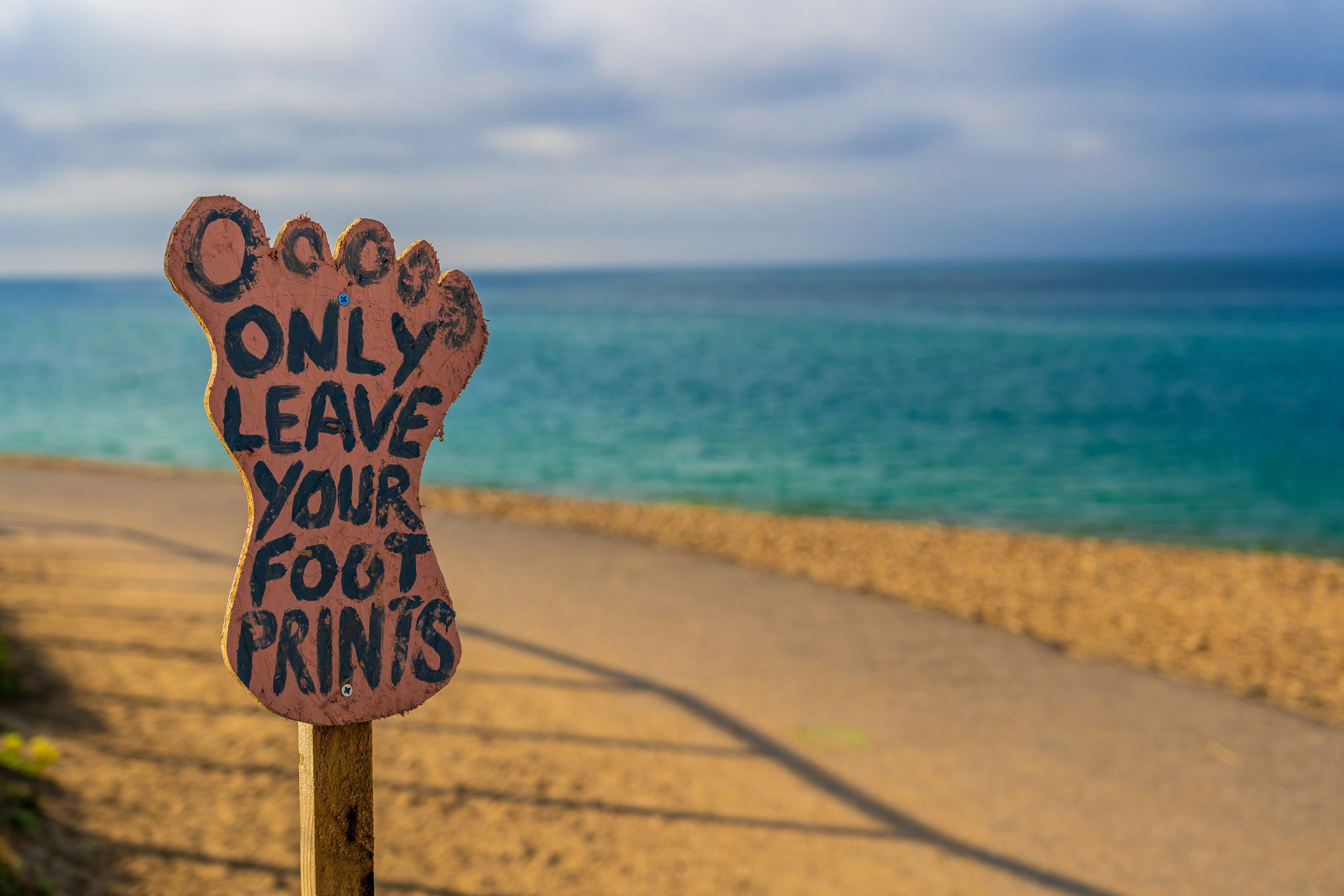 Ditch Single-Use Plastics | Beach sign reading “Only Leave Your Footprints” | Evolve Tours